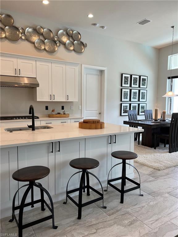 Kitchen island with light-toned countertop, integrated sink, and matte black faucet