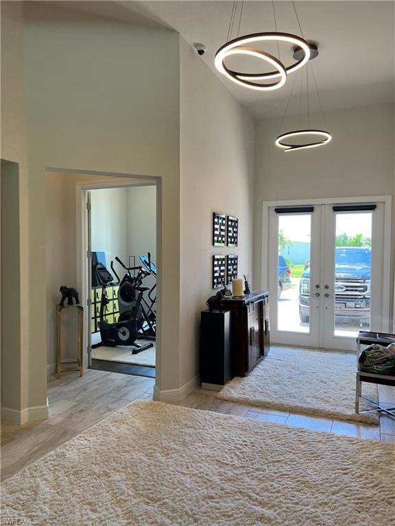 Double-door entry with frosted glass panels, featuring two circular pendant light fixtures and wood-finish flooring