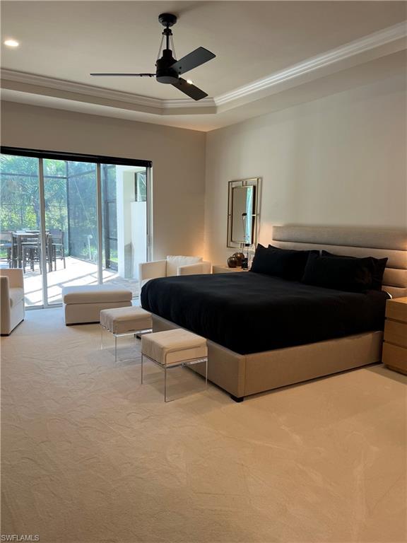 Tray ceiling with crown molding and ceiling fan, large sliding glass door, and neutral-toned wall-to-wall carpeting