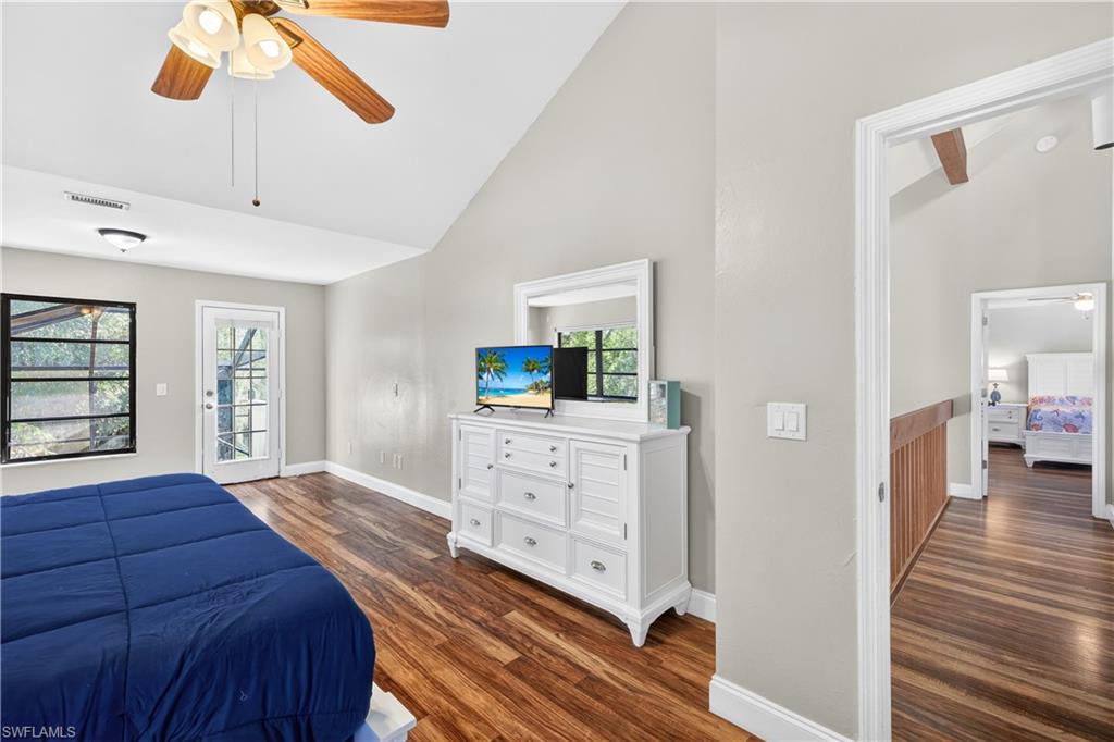 Vaulted ceilings featuring a ceiling fan, wood-finish flooring, and a glass-paned door leading to the exterior