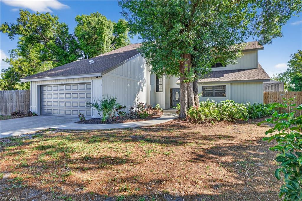 Contemporary-style home featuring a two-car garage with a paneled door, a paved driveway, a walkway to the front entrance, a dark front door with decorative glass, and established landscaping