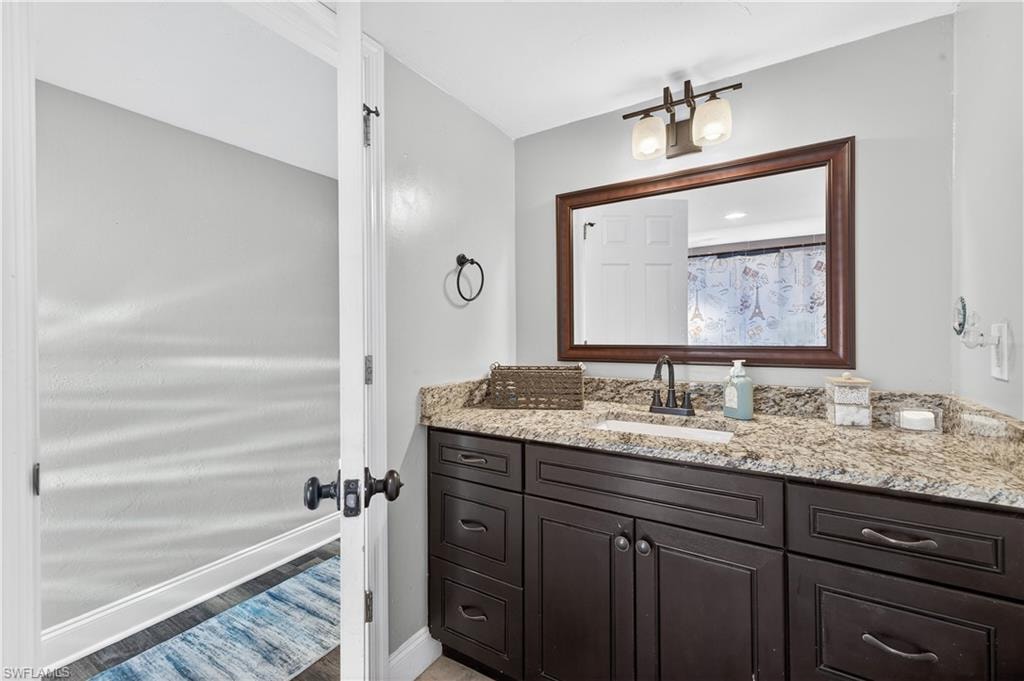Bathroom vanity featuring a granite-style countertop, undermount sink, and dark wood-finish cabinetry with multiple drawers