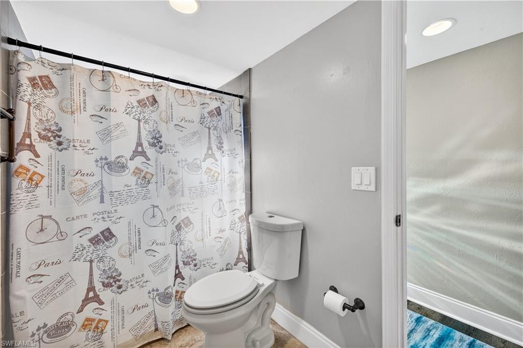 Bathroom featuring a white toilet, light gray walls, and recessed lighting