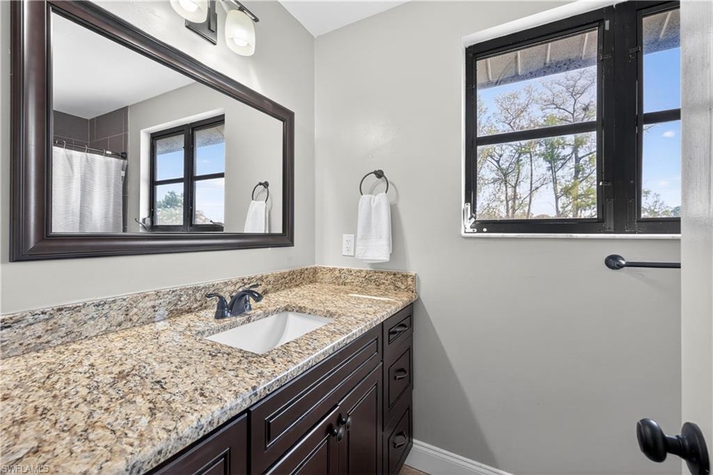 Bathroom vanity featuring a speckled countertop, undermount sink, dark wood-finish cabinetry, and a large framed mirror