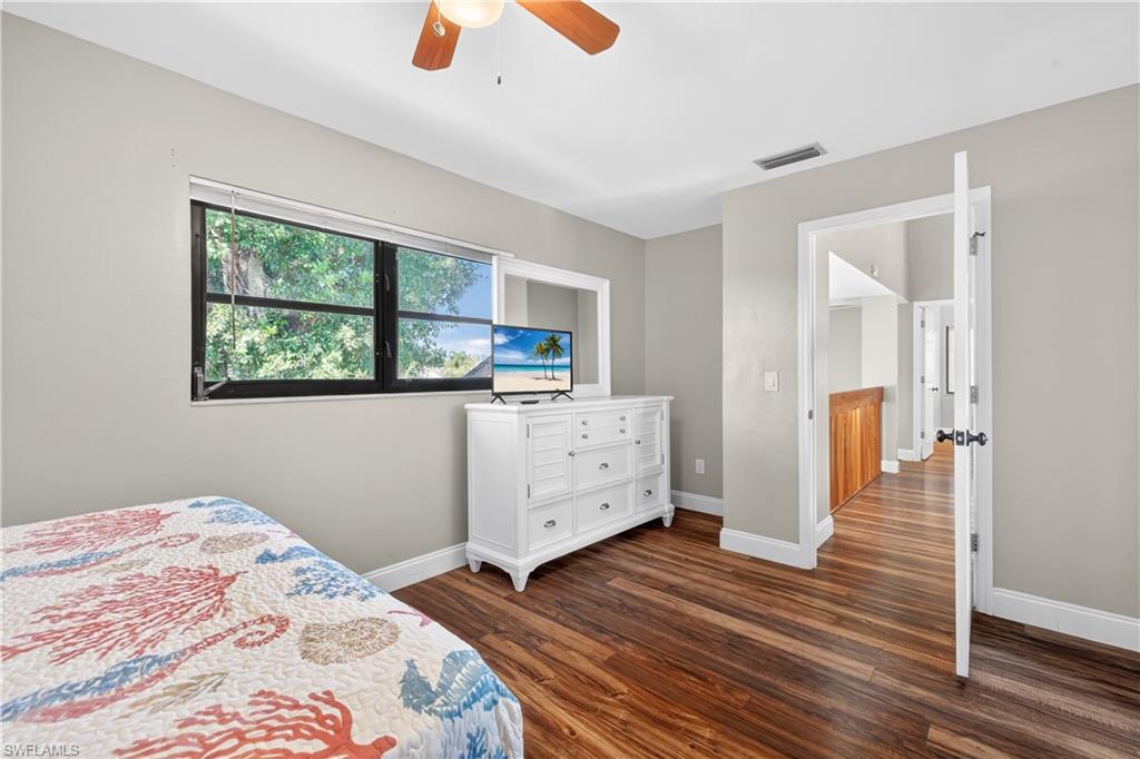 Bedroom featuring wood-finish flooring, a ceiling fan, and a large window with exterior views