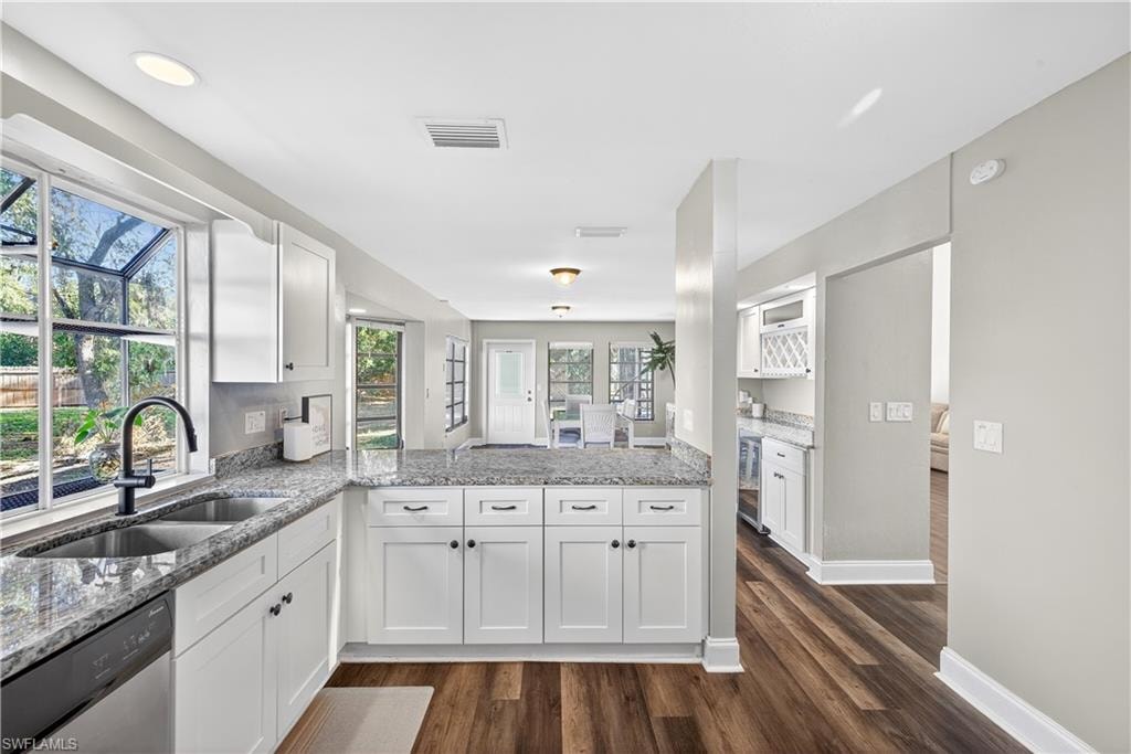 Modern kitchen featuring white shaker cabinetry, granite countertops, stainless steel double basin sink, black gooseneck faucet, and wood-finish flooring