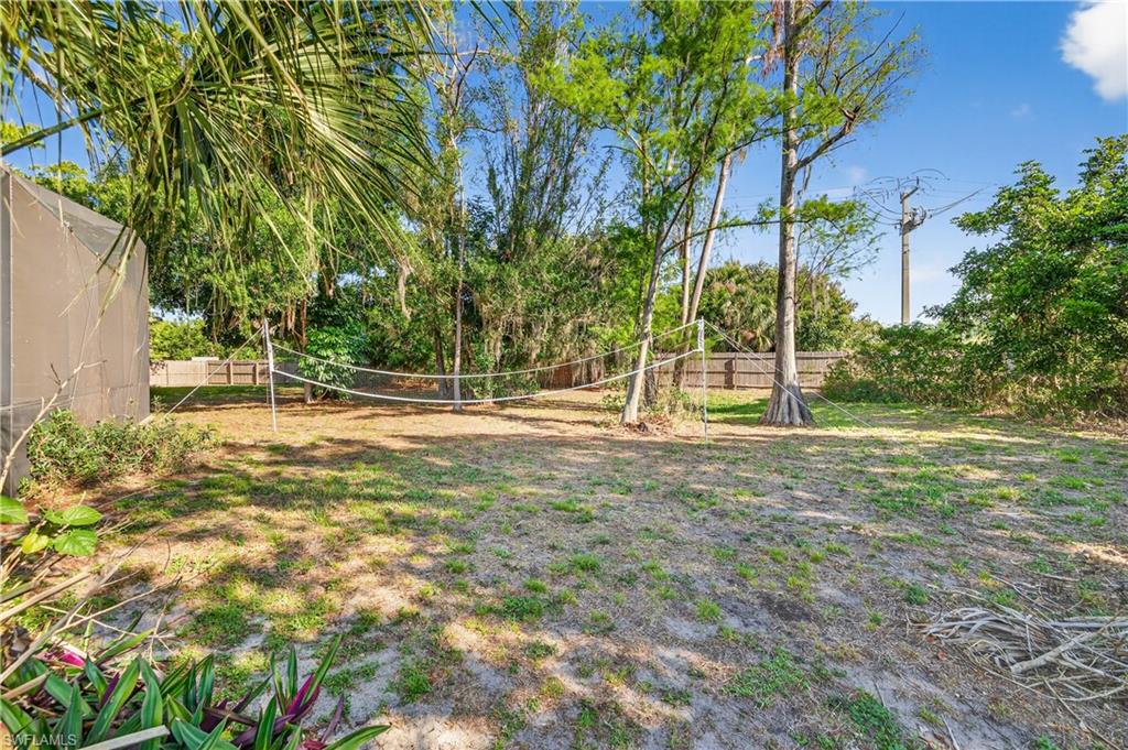 Expansive outdoor area featuring a partial privacy fence and mature trees