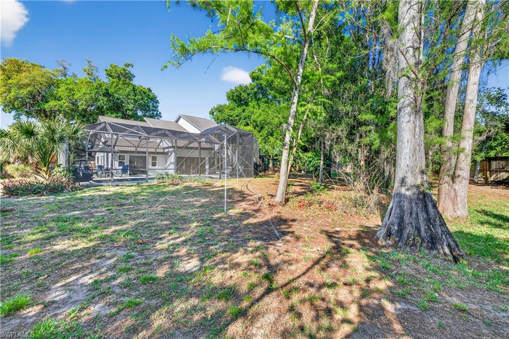 Expansive rear yard featuring mature trees and a screened patio enclosure