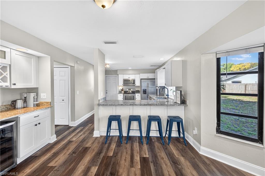 Open-concept kitchen featuring wood-finish flooring, white cabinetry, and granite countertops