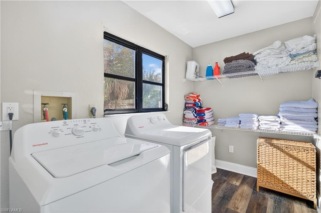 Dedicated laundry room featuring a washer and dryer, wood-finish flooring, a window with exterior visibility, overhead lighting, and built-in wire shelving