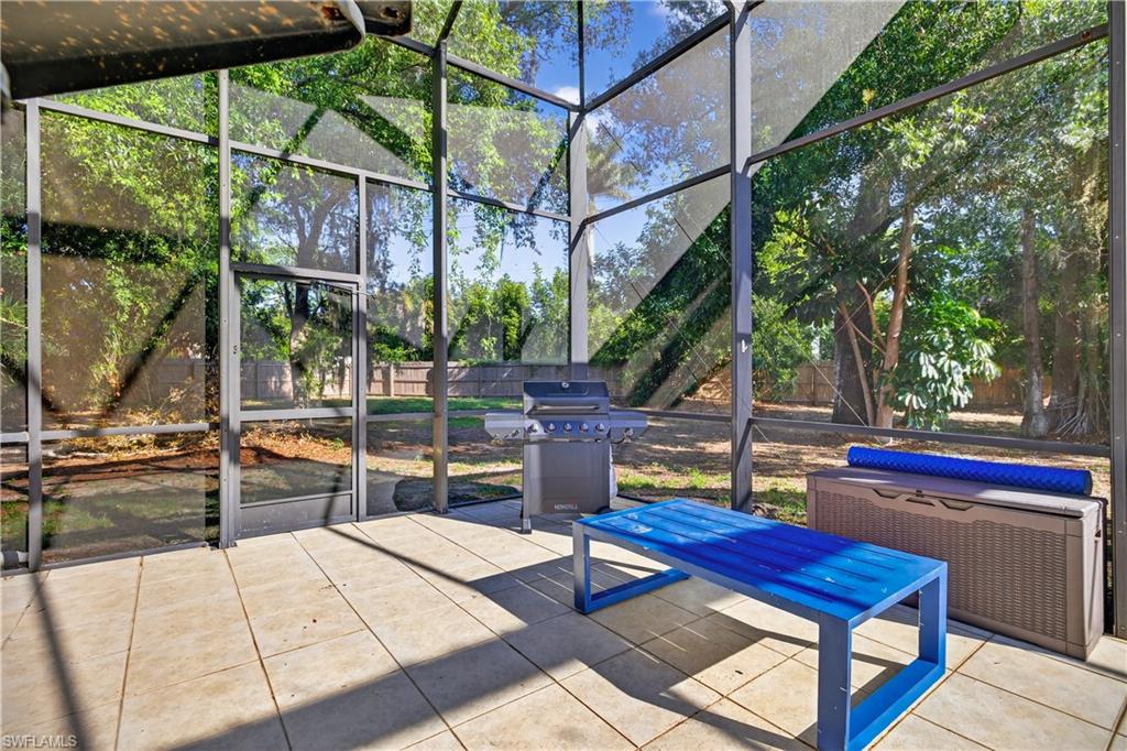 Screened enclosure with a patio featuring square tile flooring and a door providing exterior access