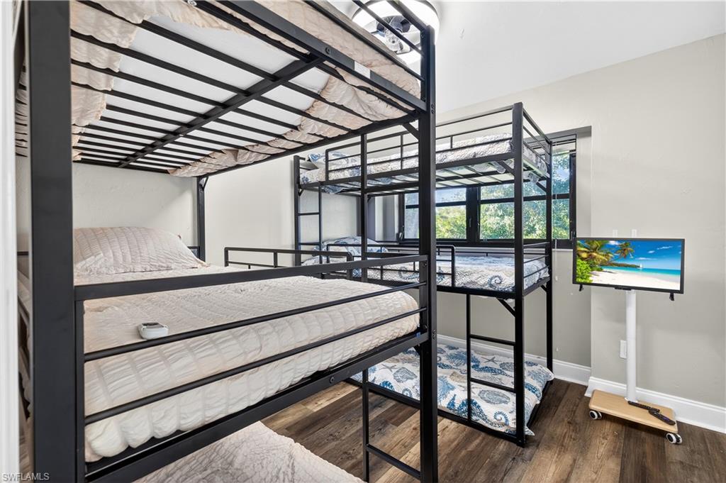 Room featuring bunk beds with black metal frames, wood-finish flooring, and light-colored walls