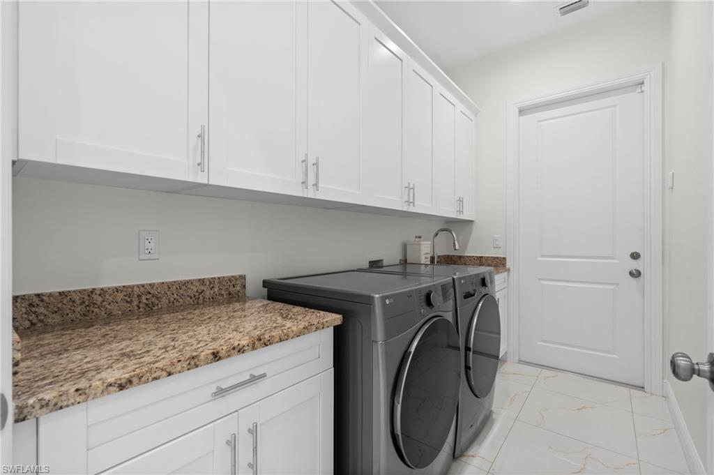 Laundry with utility sink and plenty of cabinets.