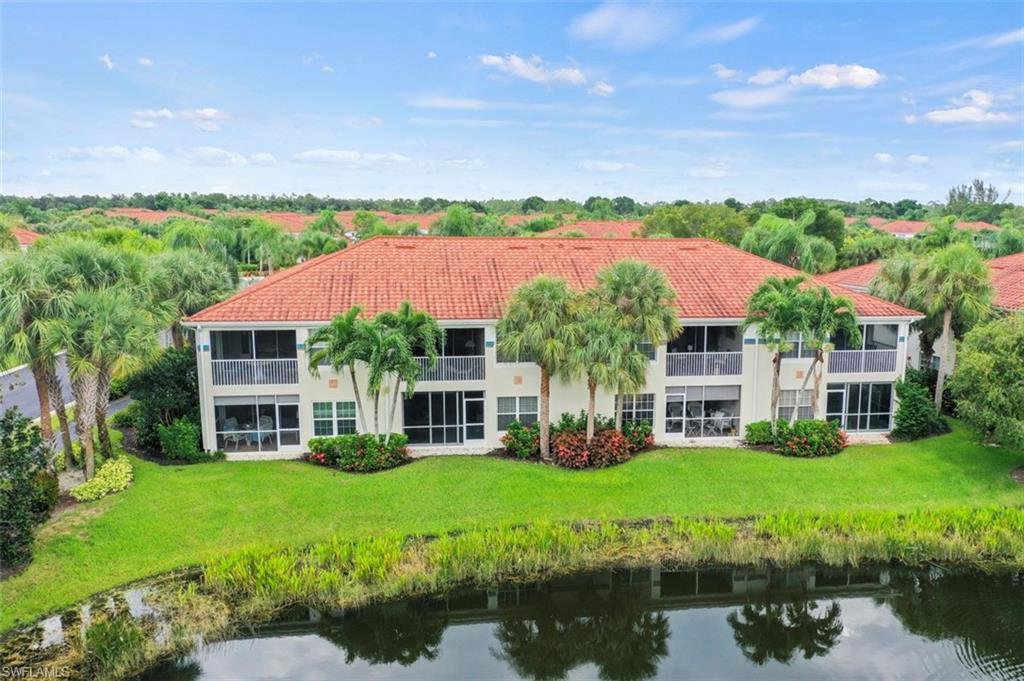 Back of house featuring a lawn and a water view