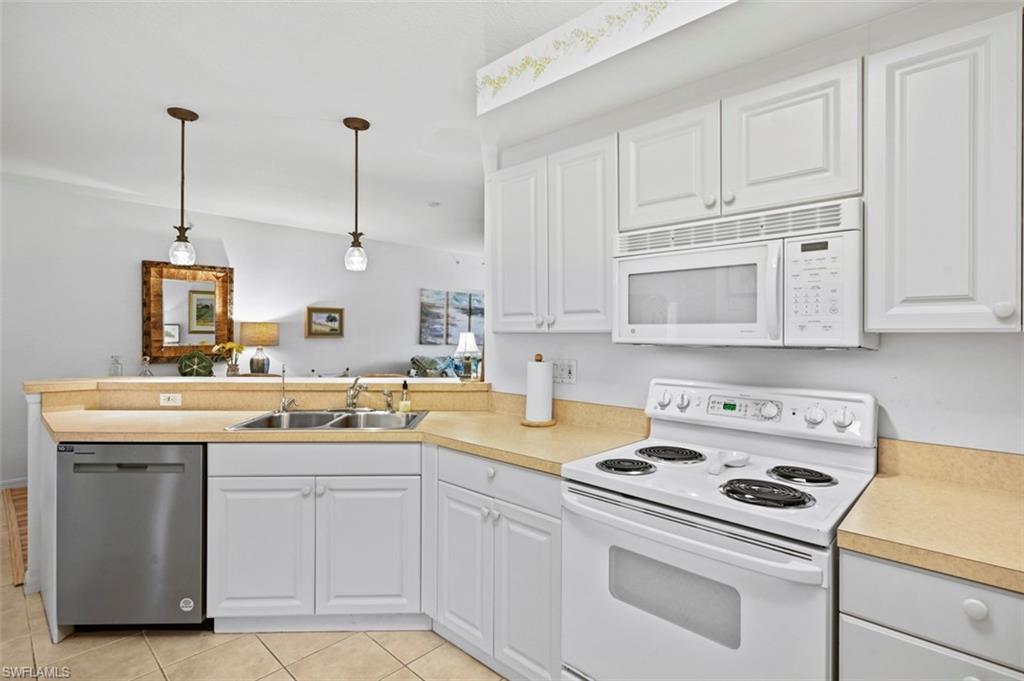 Kitchen with sink, white appliances, and white cabinetry