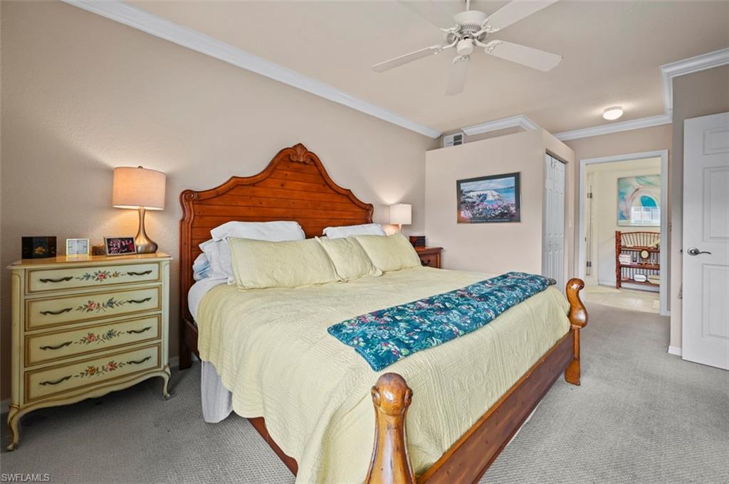 Bedroom with a closet, ceiling fan, light colored carpet, and crown molding