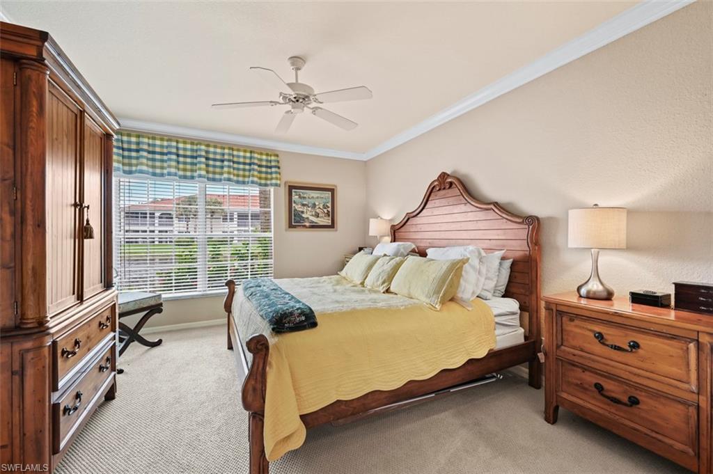 Bedroom with ceiling fan, light colored carpet, and crown molding