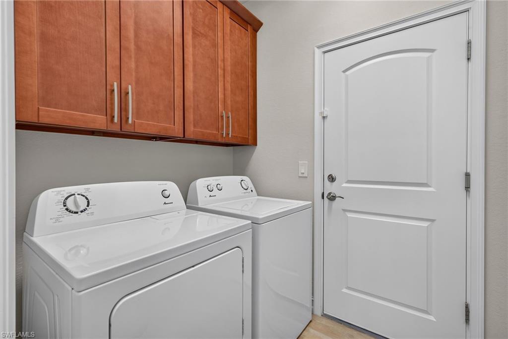 Laundry area featuring wood-finish cabinetry, light-toned wall paint, and a paneled white door with chrome hardware