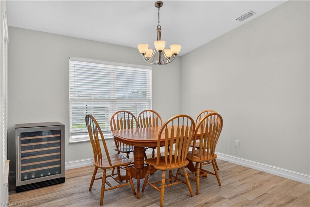 Dining area featuring wood-finish flooring, a window with blinds, and an overhead chandelier