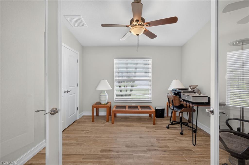Bright room featuring wood-look tile flooring, a ceiling fan with integrated lighting, and a window with horizontal blinds