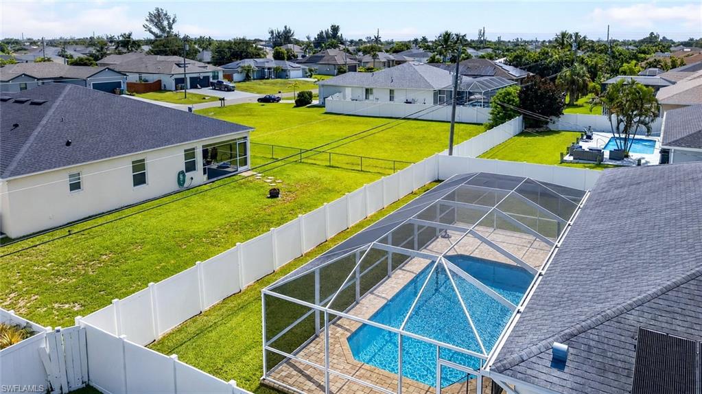 Screened swimming pool with paver decking and a white privacy fence