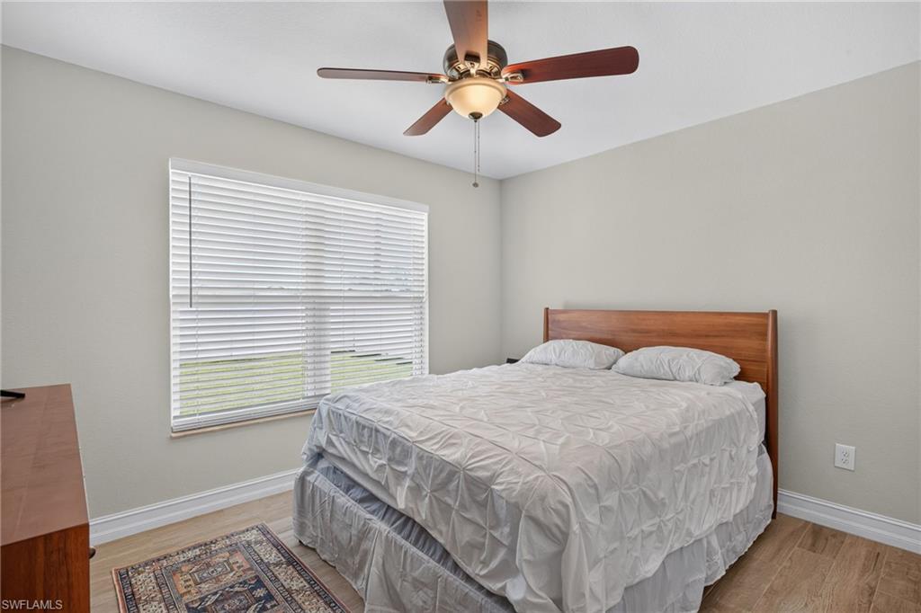 Room featuring a large window with white blinds, wood-finish flooring, and light-toned walls