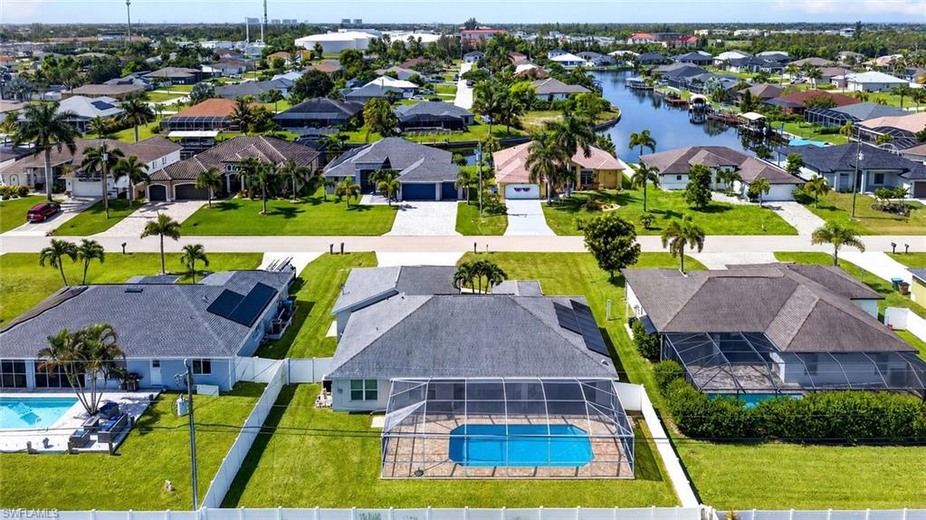 Spacious property featuring a screened-in swimming pool, a large green lawn, and a white privacy fence