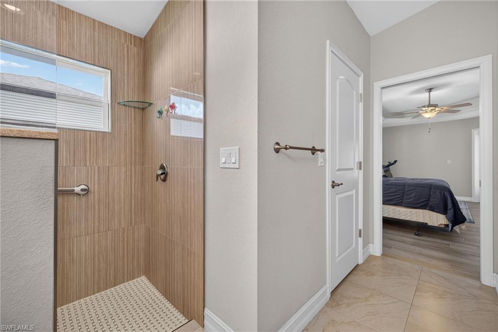 Walk-in shower featuring wood-finish tile walls, a patterned shower floor, and a clear glass enclosure