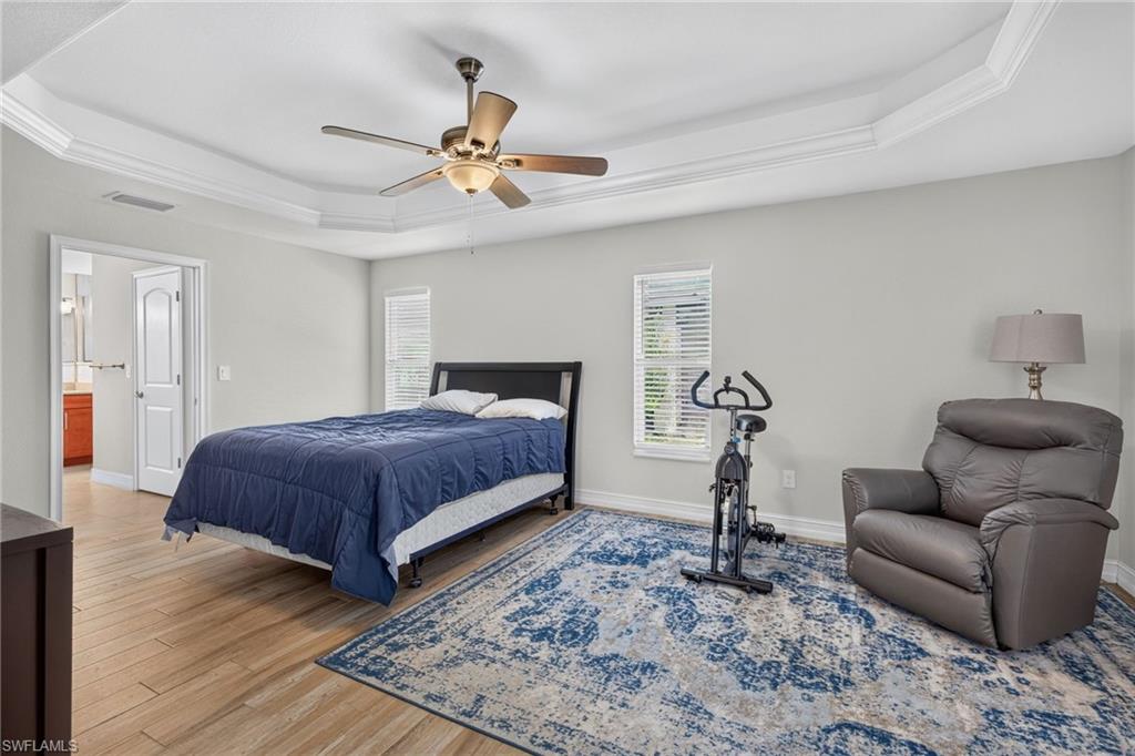 Spacious room with tray ceiling, crown molding, and a ceiling fan