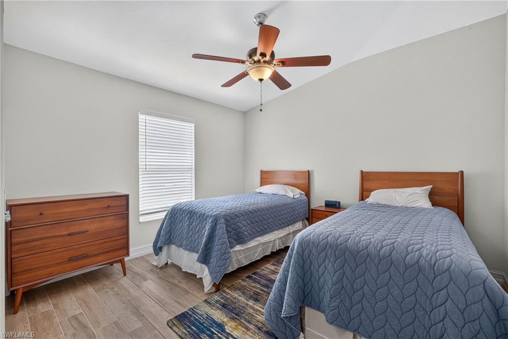 Room featuring light neutral wall paint, wood-finish flooring, a window with horizontal blinds, and an overhead ceiling fan with light fixture
