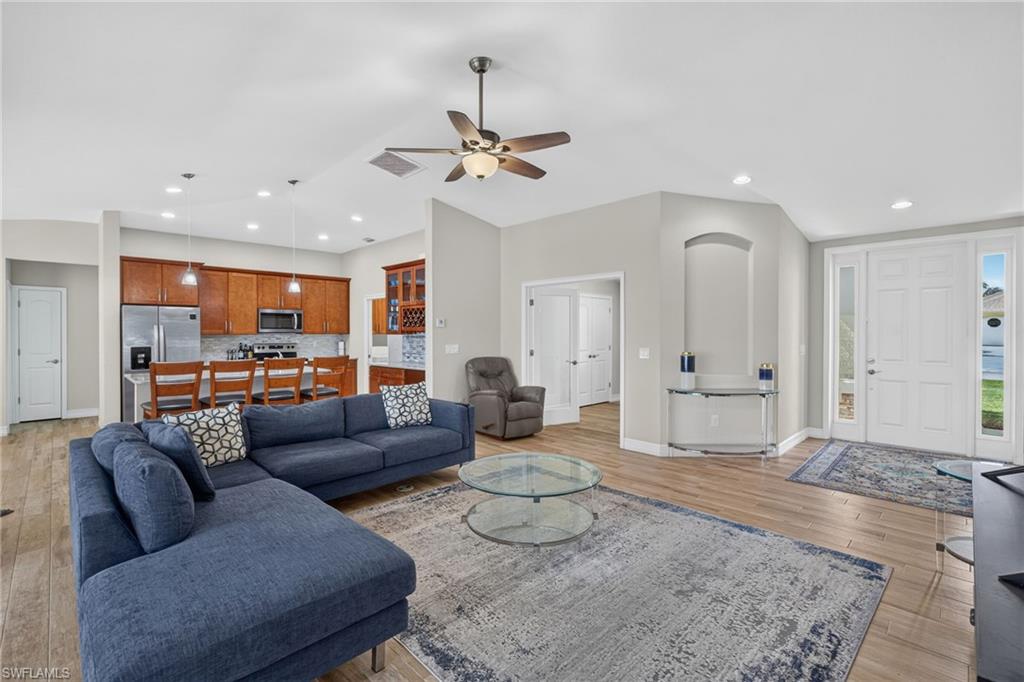 Open-concept living area featuring wood-finish flooring, a vaulted ceiling with a ceiling fan, and recessed lighting