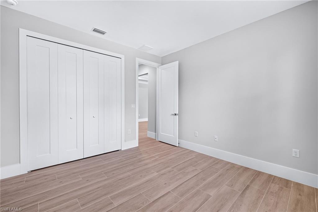 Spacious room featuring wood-finish flooring, light gray wall paint, and white trim