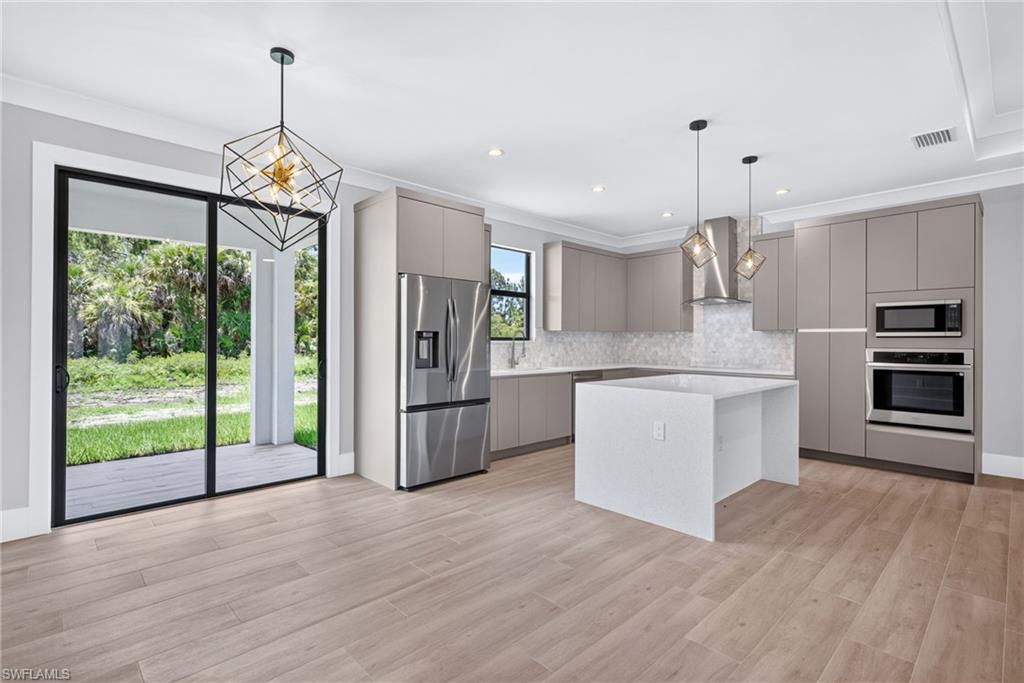 Modern kitchen featuring a waterfall island, stainless steel appliances, custom cabinetry, and wood-finish flooring
