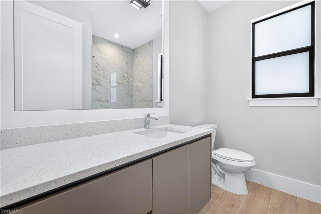 Modern bathroom featuring a single vanity with a white speckled countertop, integrated sink, and contemporary faucet