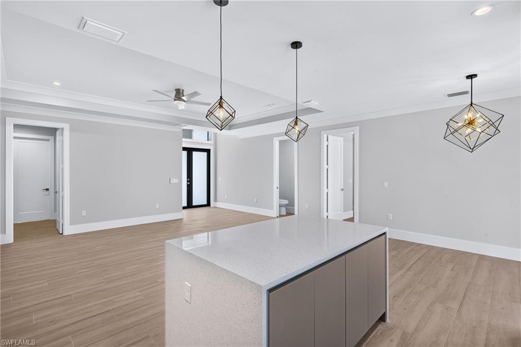 Kitchen island with a light-toned countertop, wood-finish flooring, contemporary pendant lighting, recessed lighting, and ceiling fan