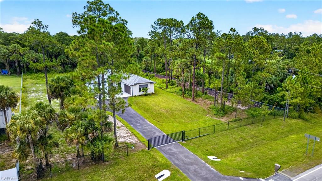 Paved driveway with gated entry, surrounded by mature trees and natural landscaping
