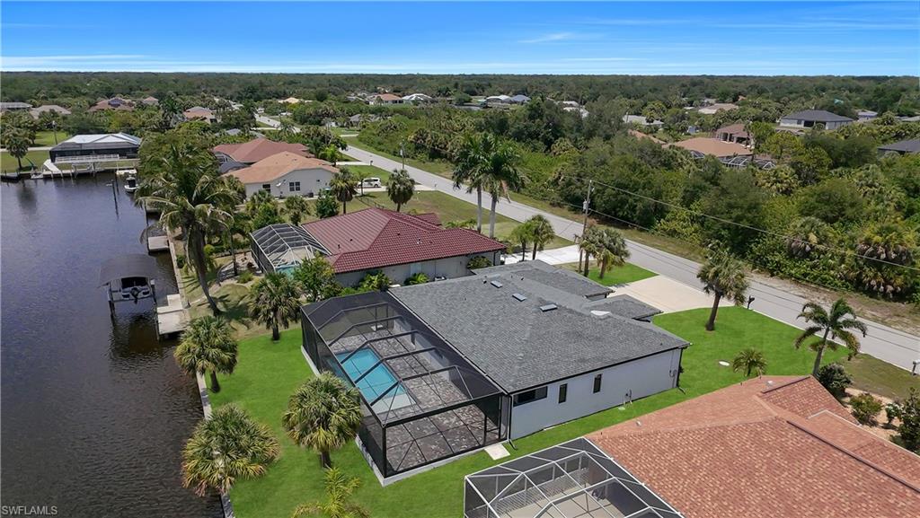 Canal-front property featuring a screened-in pool enclosure, private dock, and mature palm trees