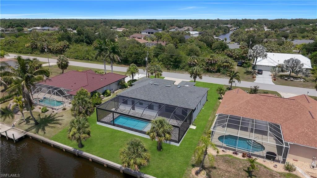 Contemporary single-story residence featuring a screened pool enclosure and manicured lawn