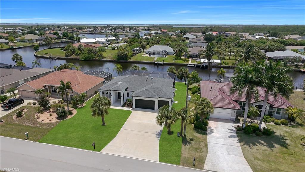 Waterfront residence with a screened lanai, boat dock, mature landscaping, and an attached two-car garage