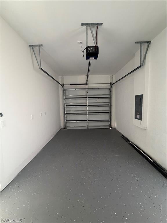 Single-car garage featuring a gray epoxy-coated floor, automatic garage door opener, and a wall-mounted electrical panel