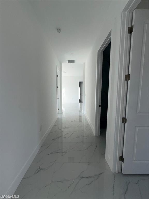 Hallway featuring polished tile flooring with a marble-like pattern, white walls, and bright white trim