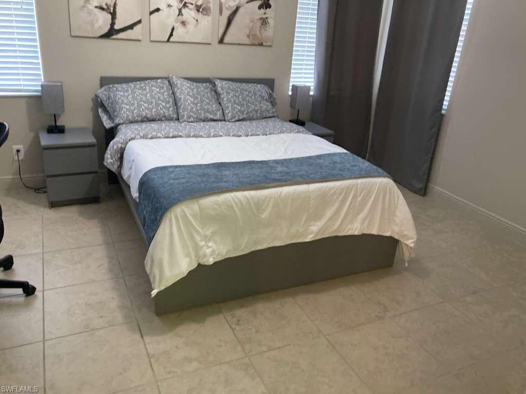 Bedroom space featuring neutral wall paint and light-toned floor tiling