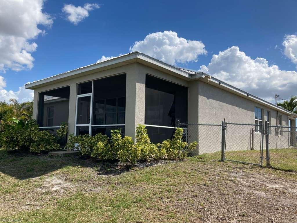 Rear exterior featuring a screened-in patio, stucco siding, and a chain-link fence