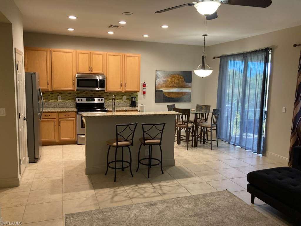 Open-concept living space featuring a kitchen with wood cabinetry, stainless steel appliances, and a mosaic tile backsplash