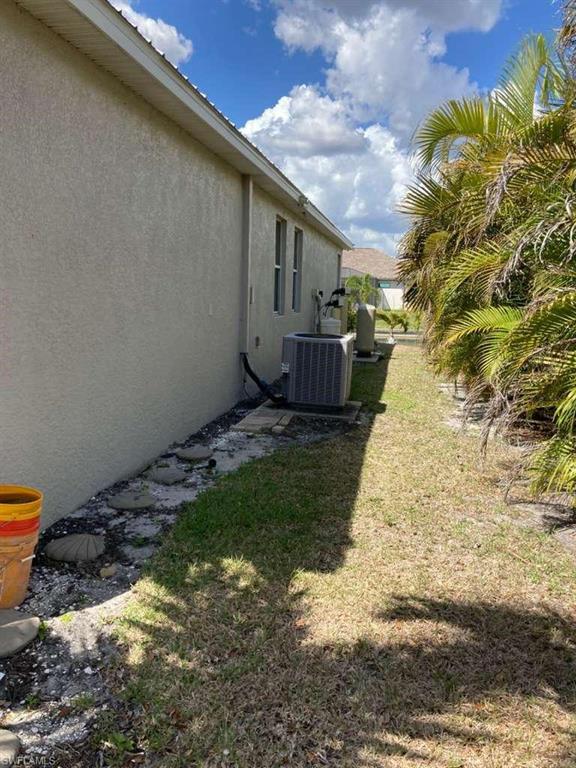 Stucco exterior with multiple windows, an air conditioning unit, and a concrete paver walkway