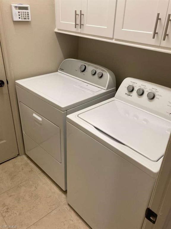 Dedicated laundry area featuring white upper cabinetry with brushed nickel hardware, a built-in shelf, and tile flooring
