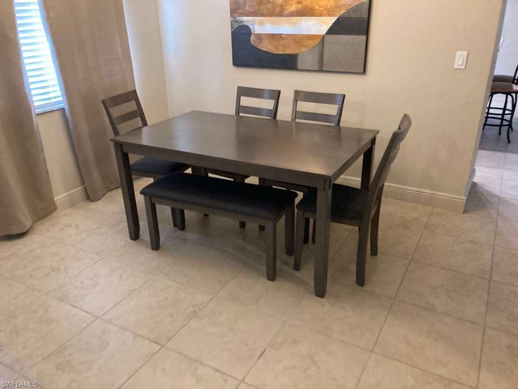 Dining area featuring light-toned tile flooring, neutral wall paint, and a window with horizontal blinds