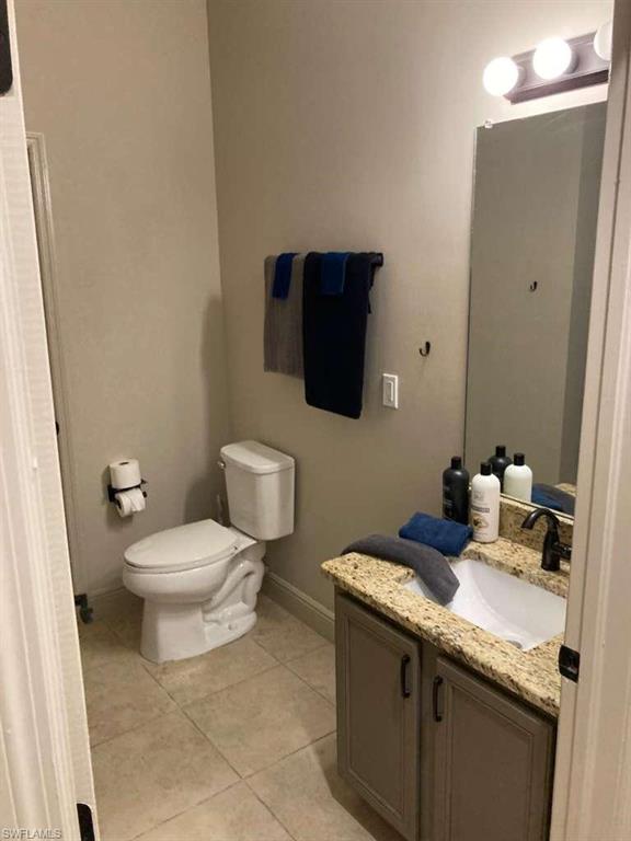 Bathroom featuring a single vanity with stone-finish countertop, undermount sink, and matte black faucet