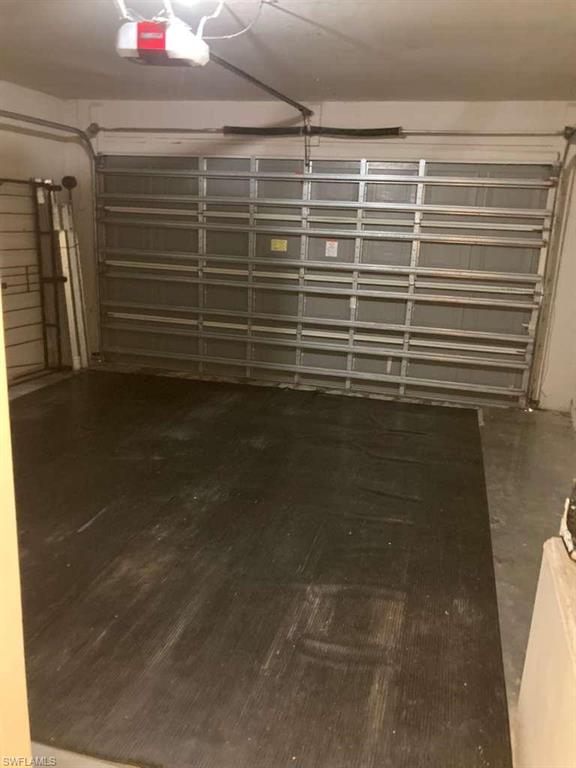 Attached garage space featuring a roll-up garage door, automatic garage door opener, and concrete flooring