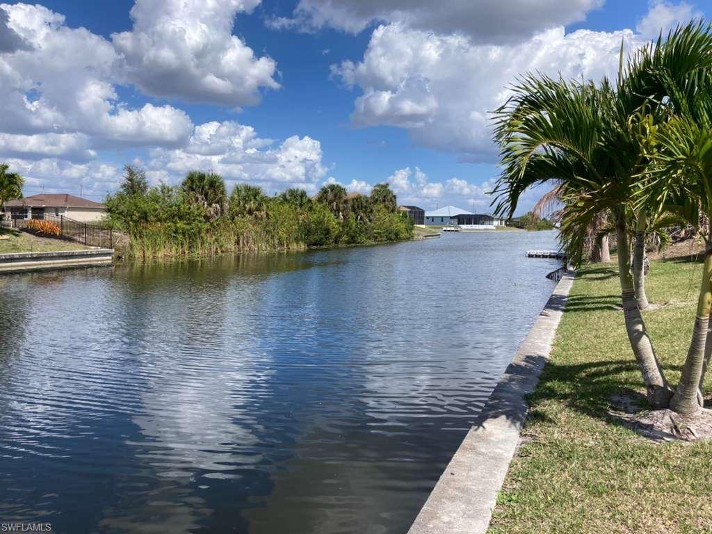 Expansive waterfront featuring a wide canal, lush tropical foliage, and mature palm trees